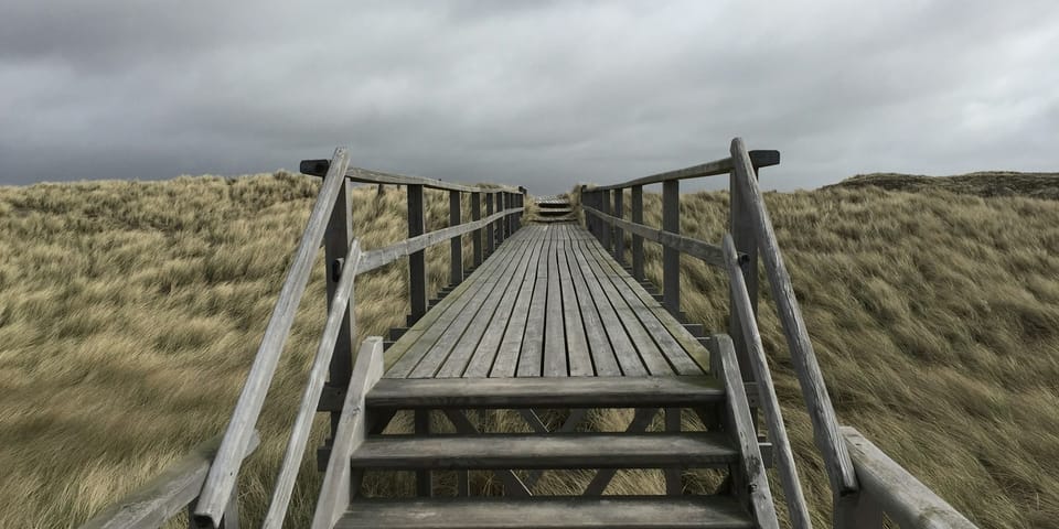 A wooden bridge pictured in stormy weather.